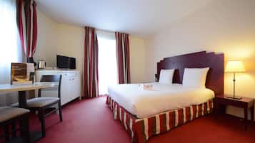 Une chambre d’hôtel avec un lit, un bureau, une chaise et une lampe.