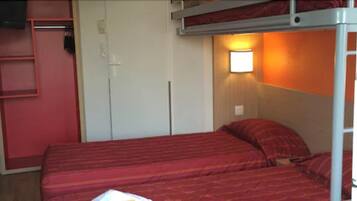 Un lit superposé avec une literie rouge, une armoire blanche et une lampe fixée au mur.