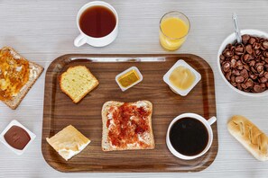 Bandeja de desayuno con tostadas, mantequilla, mermelada, café y jugo.