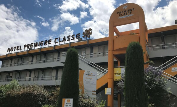 Un hotel llamado "HOTEL PREMIERE CLASSE" con un diseño arquitectónico moderno, que presenta una entrada y señalización destacadas.