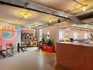 Ein modernes Interieur mit Küchenbereich, einem Essbereich mit Stühlen und Tisch sowie einer farbenfrohen Wand mit kreisförmigem Design.