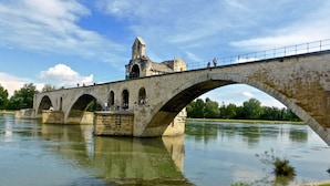 Un puente de piedra con tres arcos sobre un río, con una torre a la izquierda.
