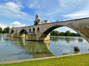 A stone bridge with three arches over a river, featuring a tower on the left side.