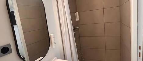 A modern bathroom with a shower, a sink, a mirror, and a light fixture.