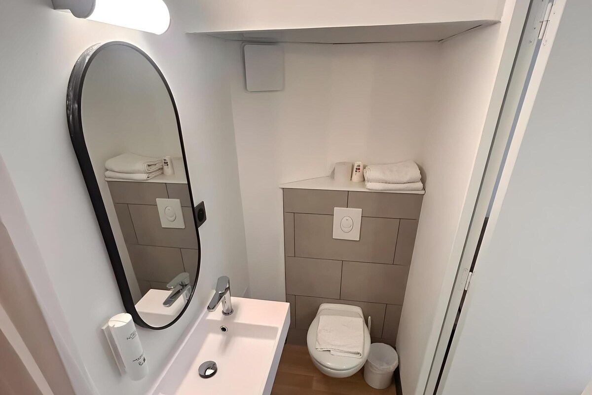 A modern bathroom with a white sink, mirror, and toilet.