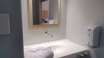 Un baño moderno con un lavabo blanco, un espejo y un dispensador de gel antibacterial.