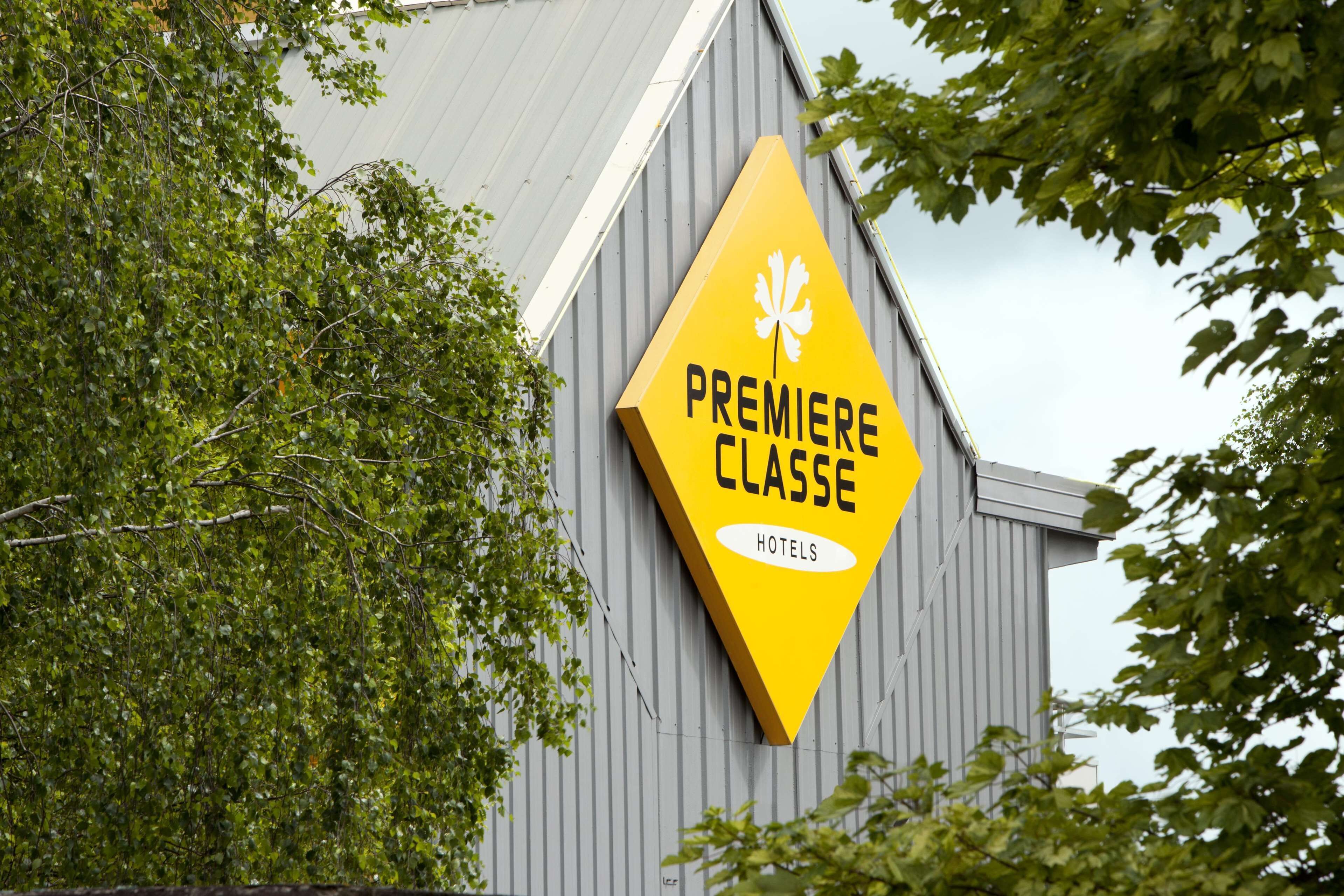 A yellow diamond-shaped sign with the text "PREMIERE CLASSE HOTELS" on a building.