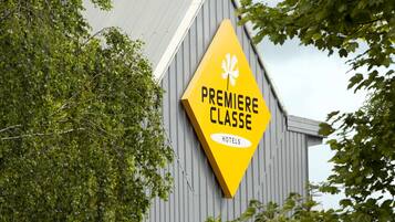 Ein gelbes, rautendes Schild mit der Aufschrift 'PREMIERE CLASSE HOTELS' an einem Gebäude.