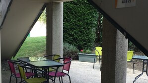 Un patio al aire libre con una mesa y sillas, rodeado de pilares de hormigón.