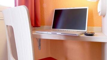 Ein Laptop steht auf einem Holztisch zusammen mit einem roten Stuhl.