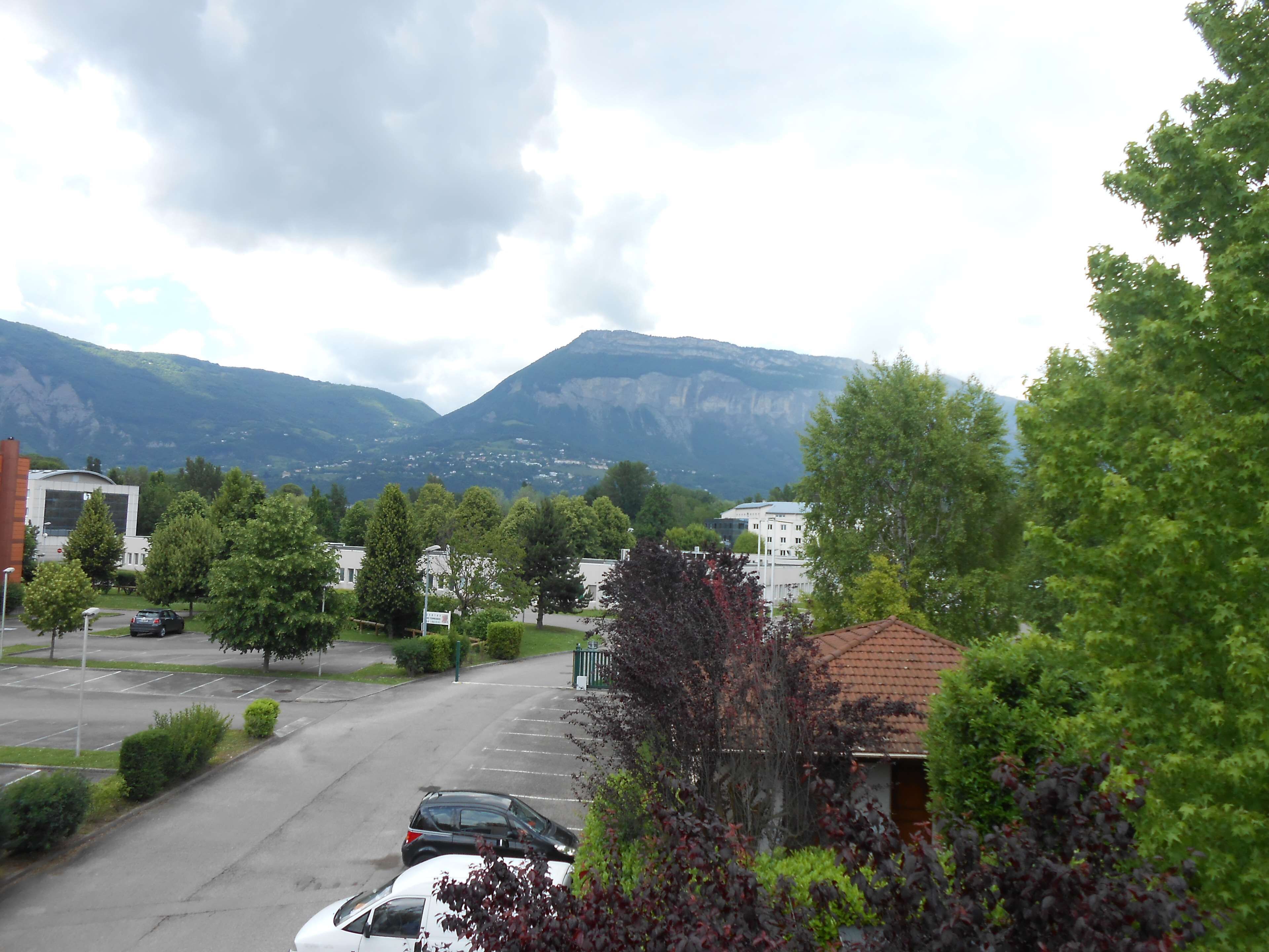 A parking lot with several cars, surrounded by trees and buildings.