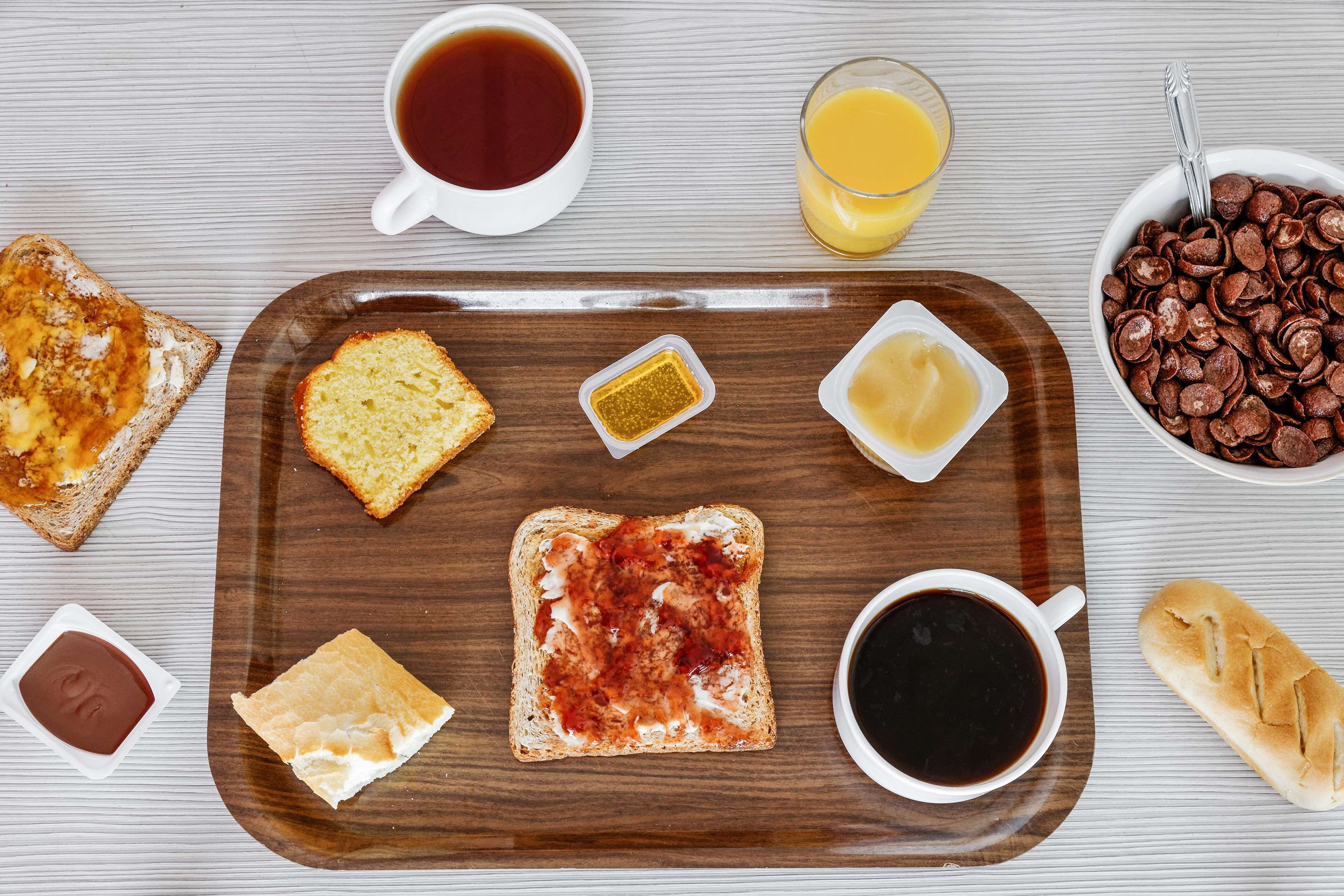 A breakfast tray with toast, butter, jam, coffee, and juice.
