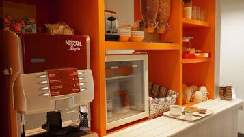 Una estación de café Nescafé con diversas opciones de café y un refrigerador.