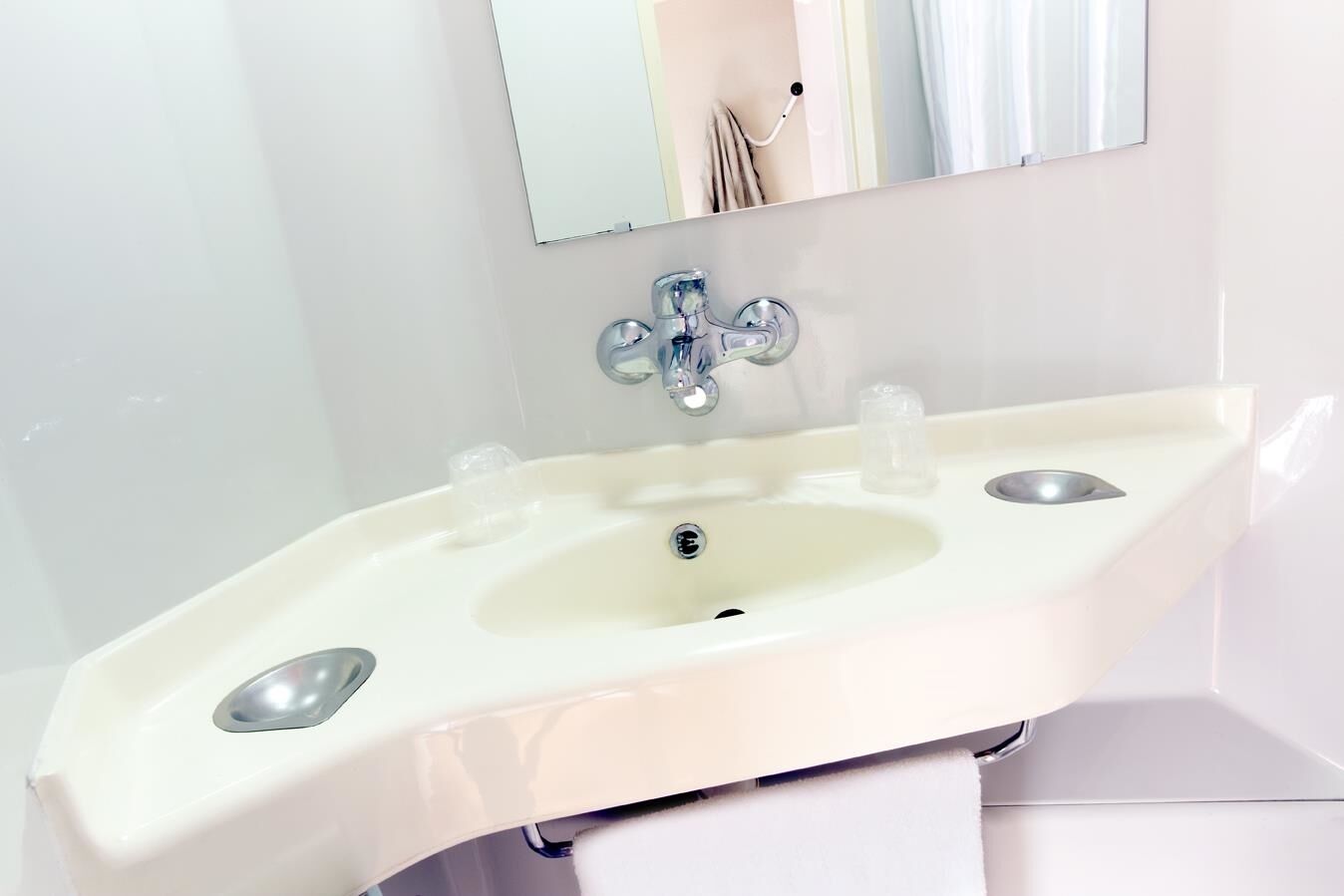 Ein Badezimmer mit einem weißen Waschbecken, einem Spiegel darüber und einem Handtuch an einem Wäscheständer.
