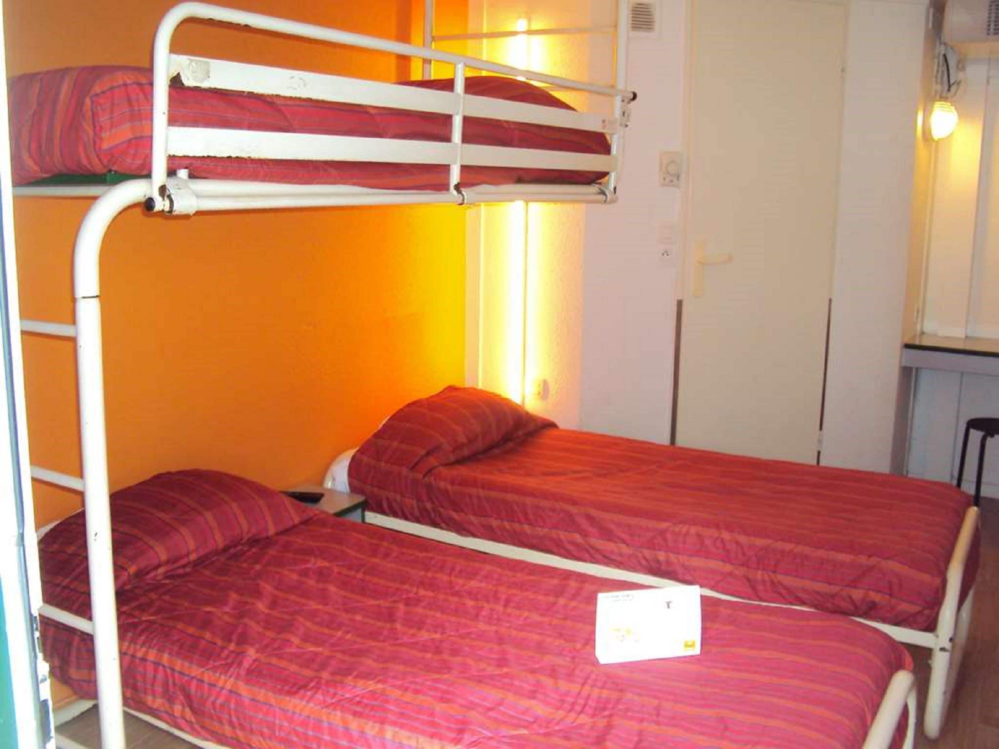 A bunk bed room with two beds, orange walls, and a small desk with a chair.