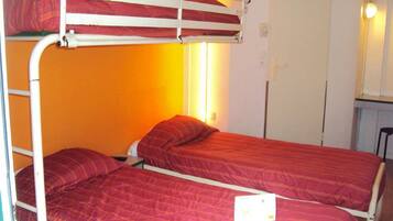 A bunk bed room with two beds, orange walls, and a small desk with a chair.