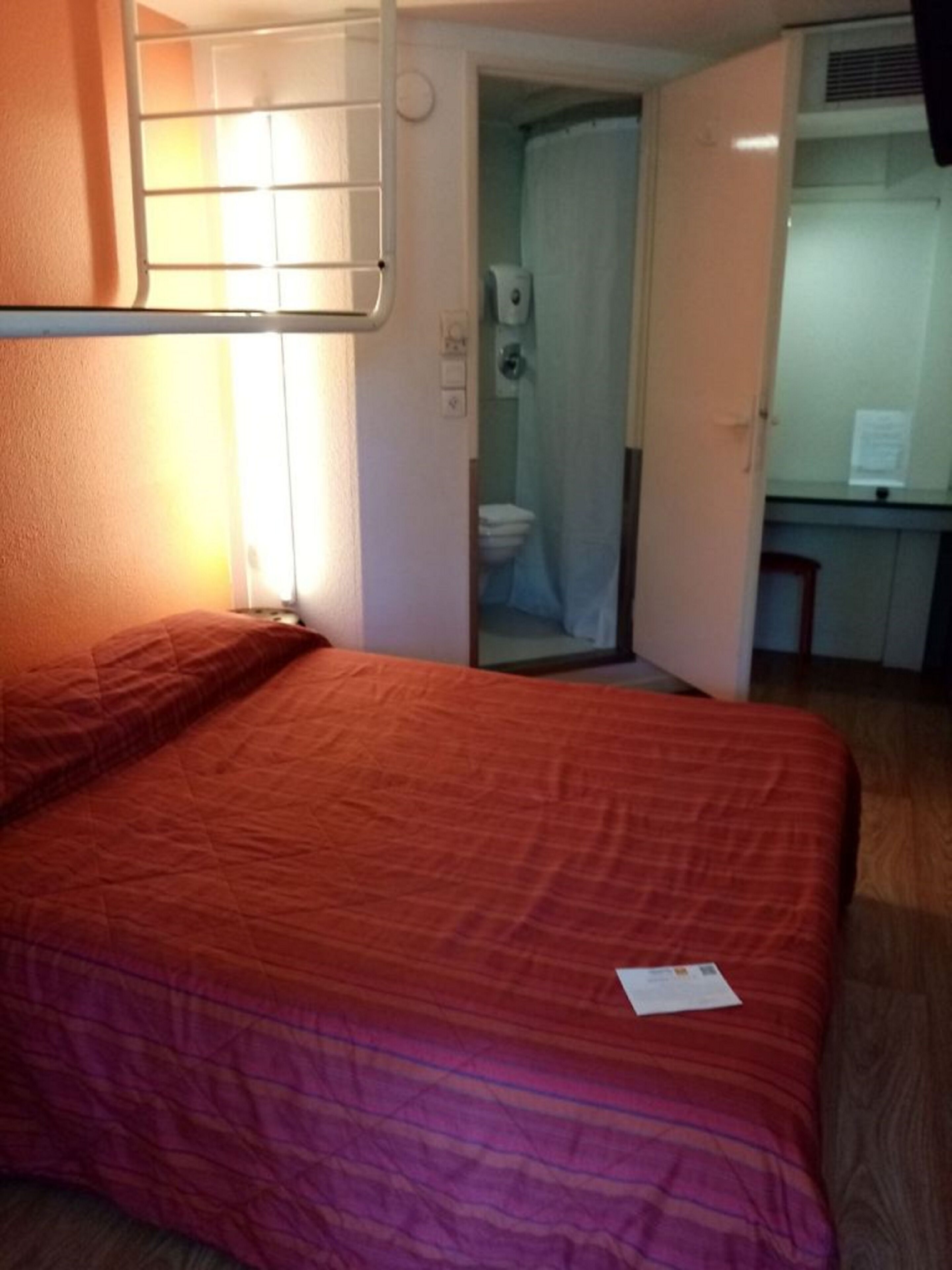 Una habitación con cama, baño y una pequeña kitchenette.