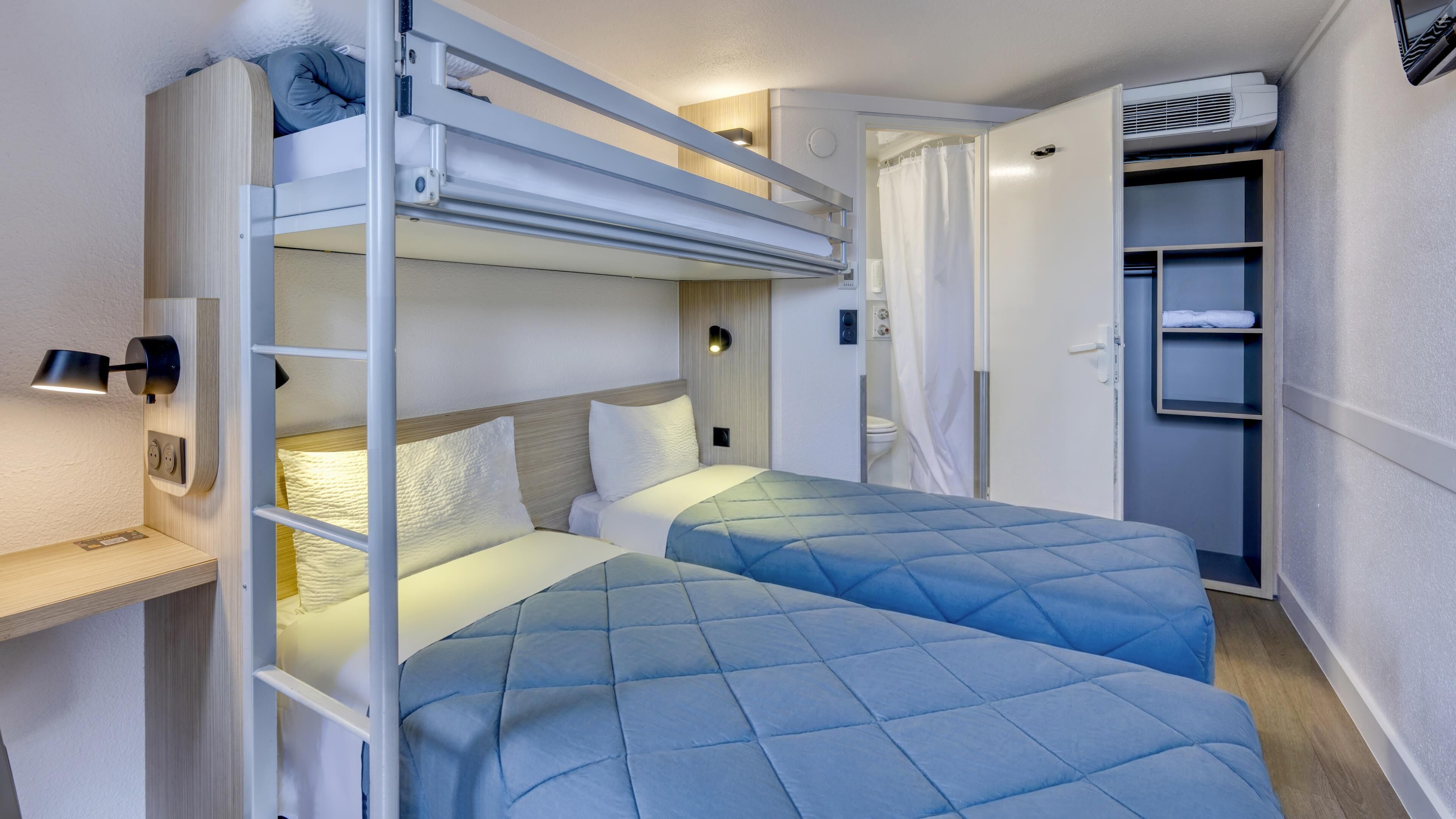 Une chambre avec un lit superposé, un bureau, une étagère et une armoire.
