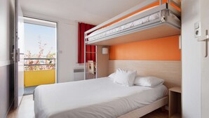 Habitación de hotel con literas, un escritorio, una silla y una puerta corredera a un balcón.