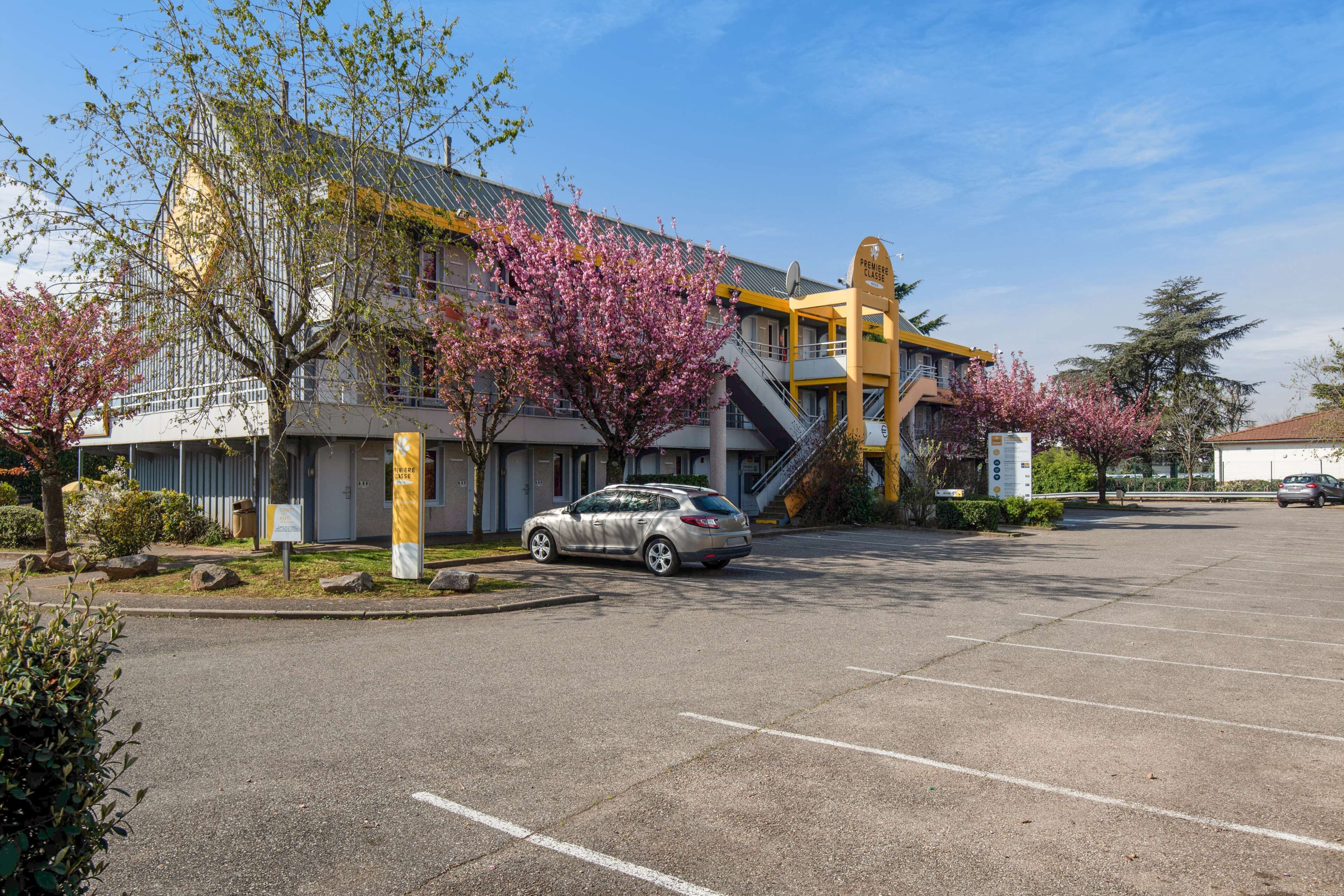 A parking lot with a building that has a yellow and white facade, a staircase, and a sign that reads "Police Class."