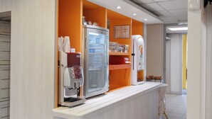 Una cocina moderna con refrigerador integrado, cafetera y detalles en color naranja.