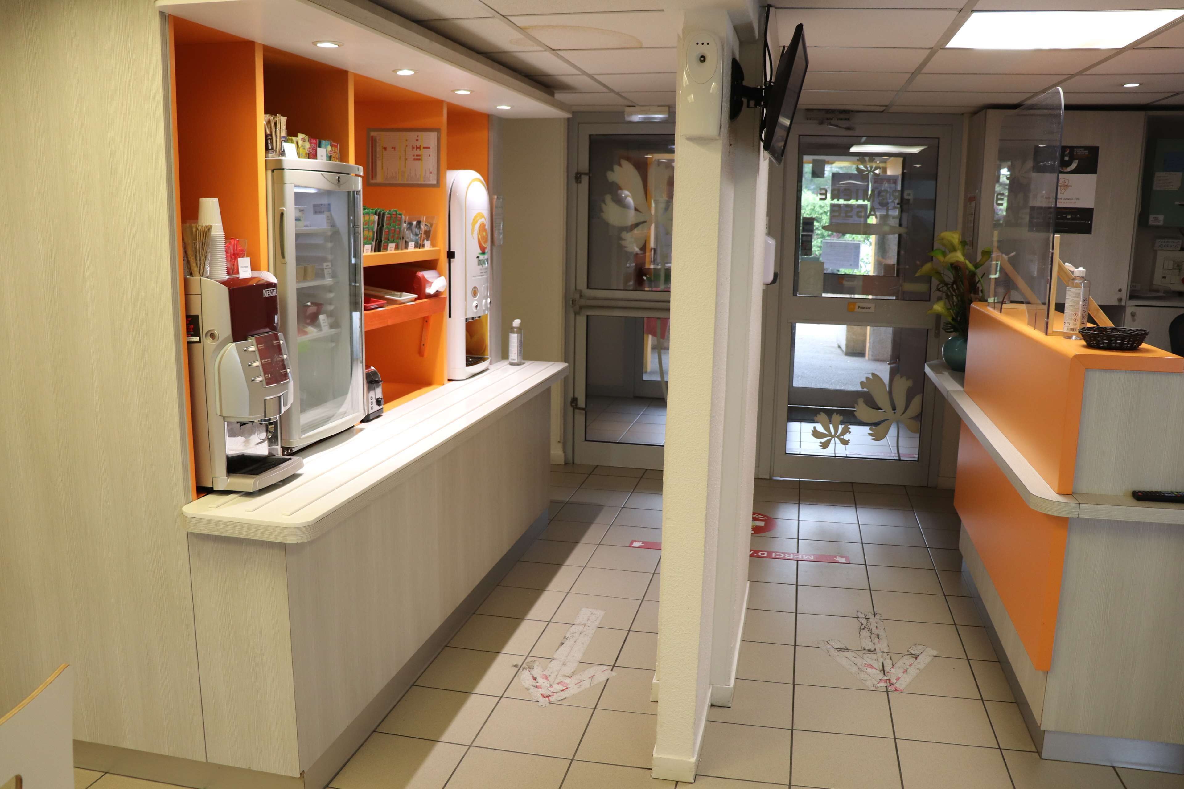 Un hall de hotel con mostrador de recepción, refrigerador y máquina expendedora.