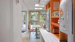 Interior de una cafetería moderna y limpia, con mostrador, zona de asientos y máquina de café.