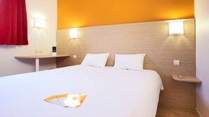 Une chambre d’hôtel avec un grand lit, deux tables de chevet et un rideau rouge.