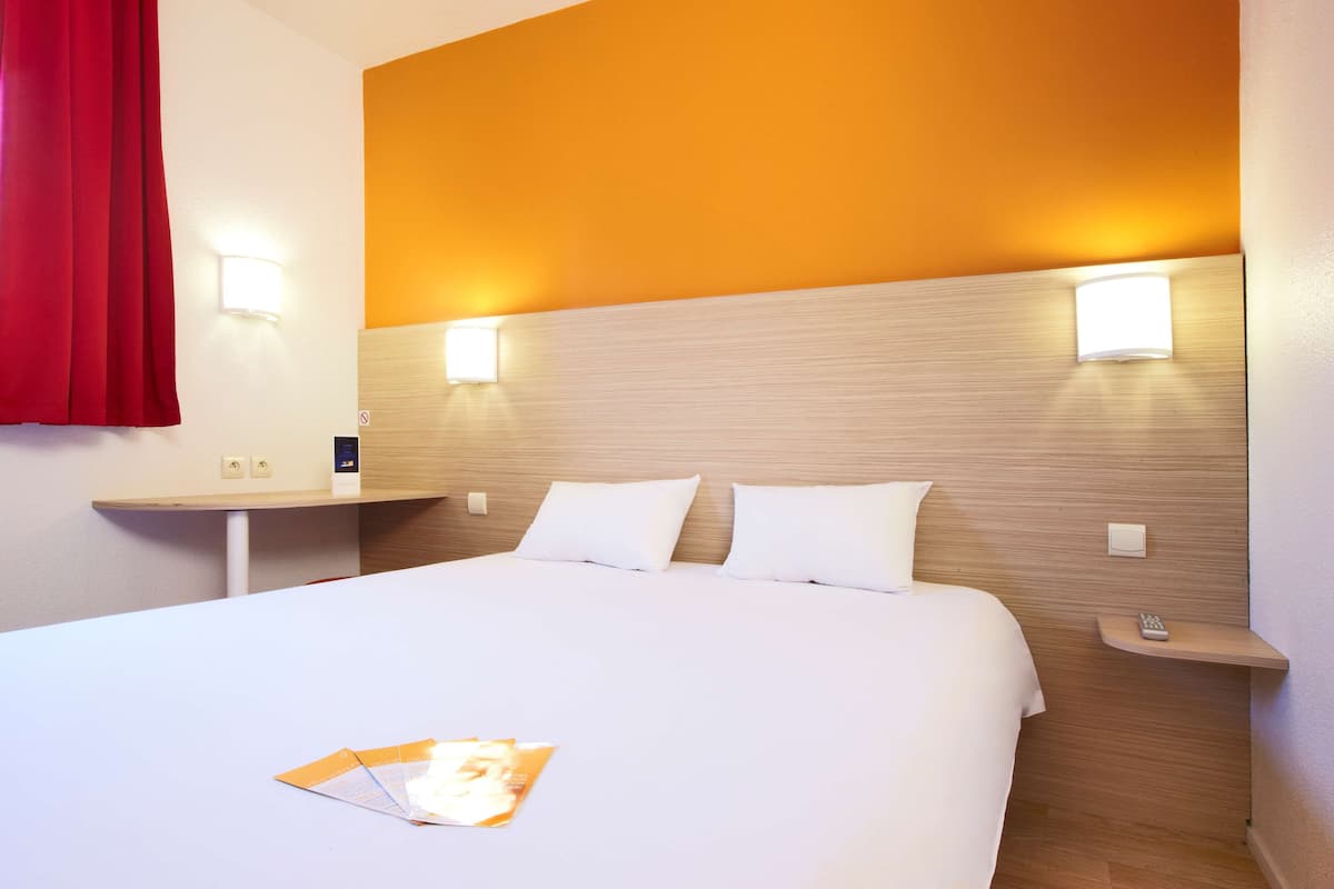 Ein Hotelzimmer mit einem großen Bett, zwei Nachttischen und einem roten Vorhang.