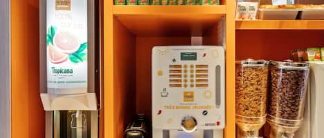 Una estación de café con una máquina de café, una cafetera y dos dispensadores de café.