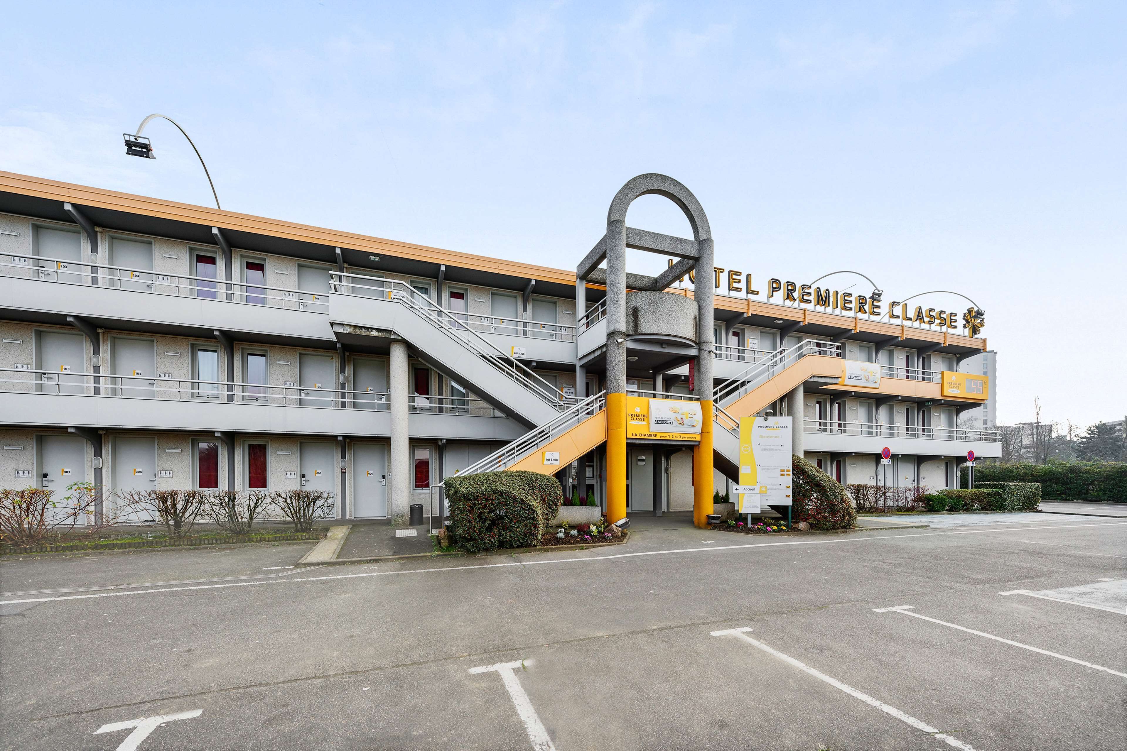 Un hotel con una entrada destacada, varios balcones y un esquema de color distintivo en amarillo y gris.