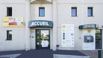 A hotel entrance with a reception desk, a sign for the hotel class, and an automatic reception sign.