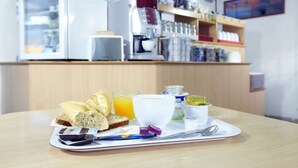 Un plateau de petit-déjeuner avec du pain, du jus et des condiments, posé sur une table dans un café.