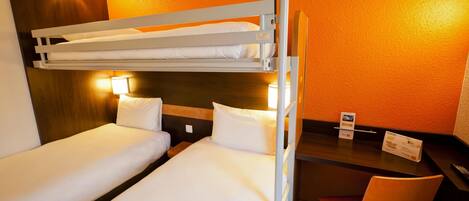 A hotel room with two bunk beds, a desk with a chair, and two bedside lamps.