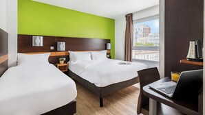 A hotel room with two beds, a desk with a laptop, a window with a city view, and a green accent wall. - Premiere Classe Lyon Centre - Gare Part Dieu (Lyon)