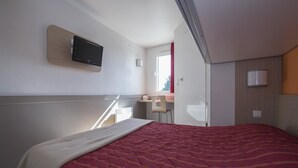 Een moderne hotelkamer met een groot bed, een bureau met stoel, een flatscreen-tv aan de muur en een raam met een rode gordijn.