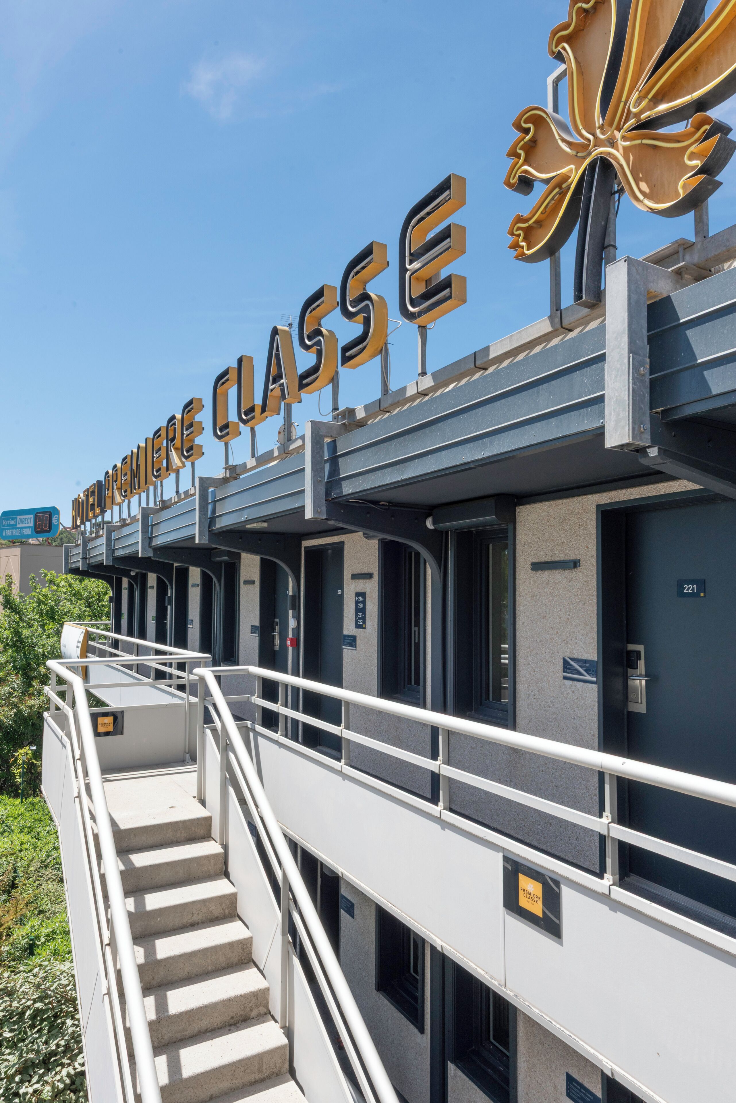 A hotel entrance with a large sign reading 'HOTEL PREMIERE CLASSE' and a staircase leading to the entrance.