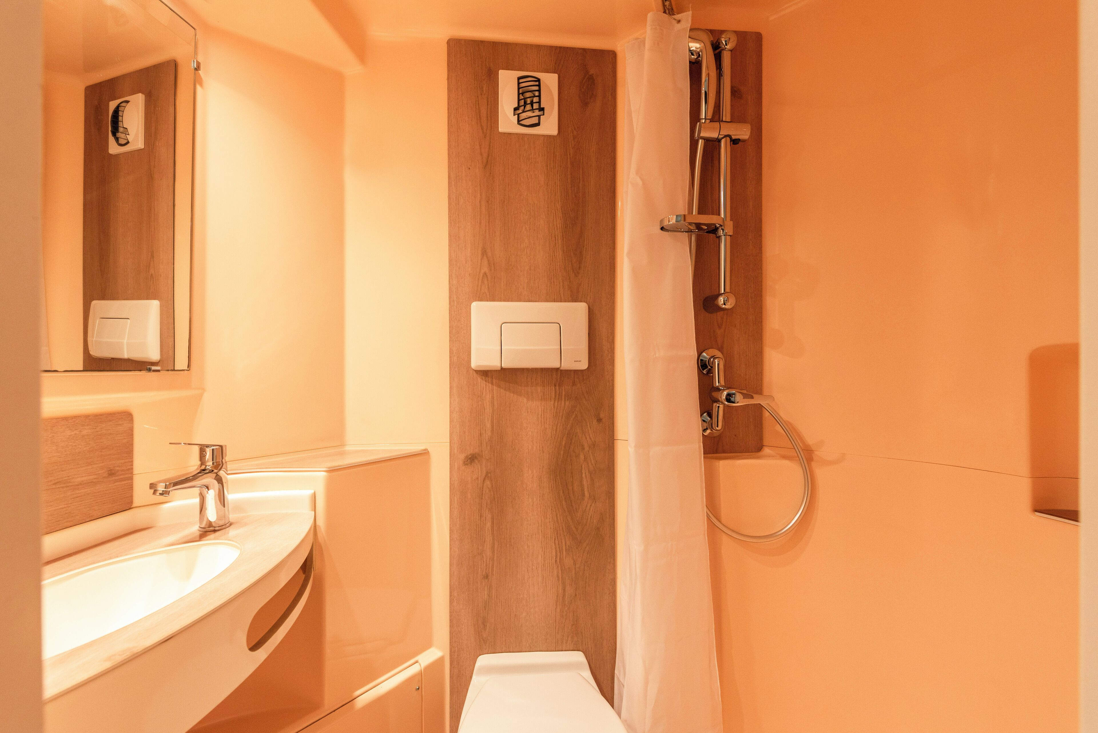 Ein Badezimmer mit einem Holzkosmetikschrank, einem Waschbecken, einem Spiegel, einer Duschkabine mit Glastür und einem Handtuchhalter.