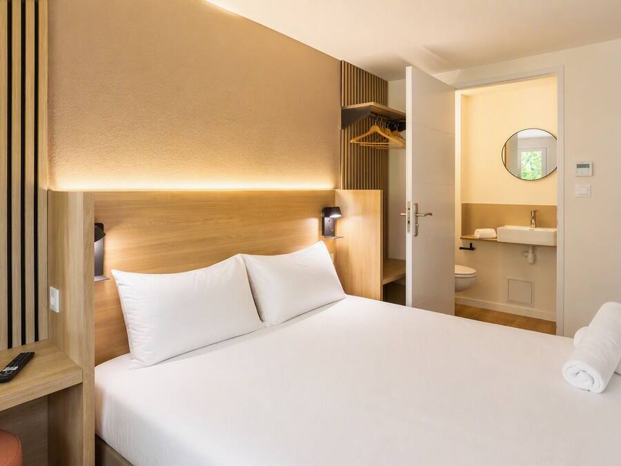 Et hotelværelse med seng, natbord og udsigt til badeværelset.