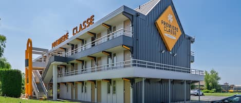 Un edificio de varios pisos con letreros de 'PREMIERE CLASSE' y un balcón, y un cartel de 'PREMIERE CLASSE HOTELS'.