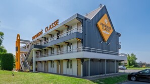 Un immeuble à plusieurs étages avec une enseigne « PREMIERE CLASSE », un balcon et une enseigne « PREMIERE CLASSE HOTELS ».