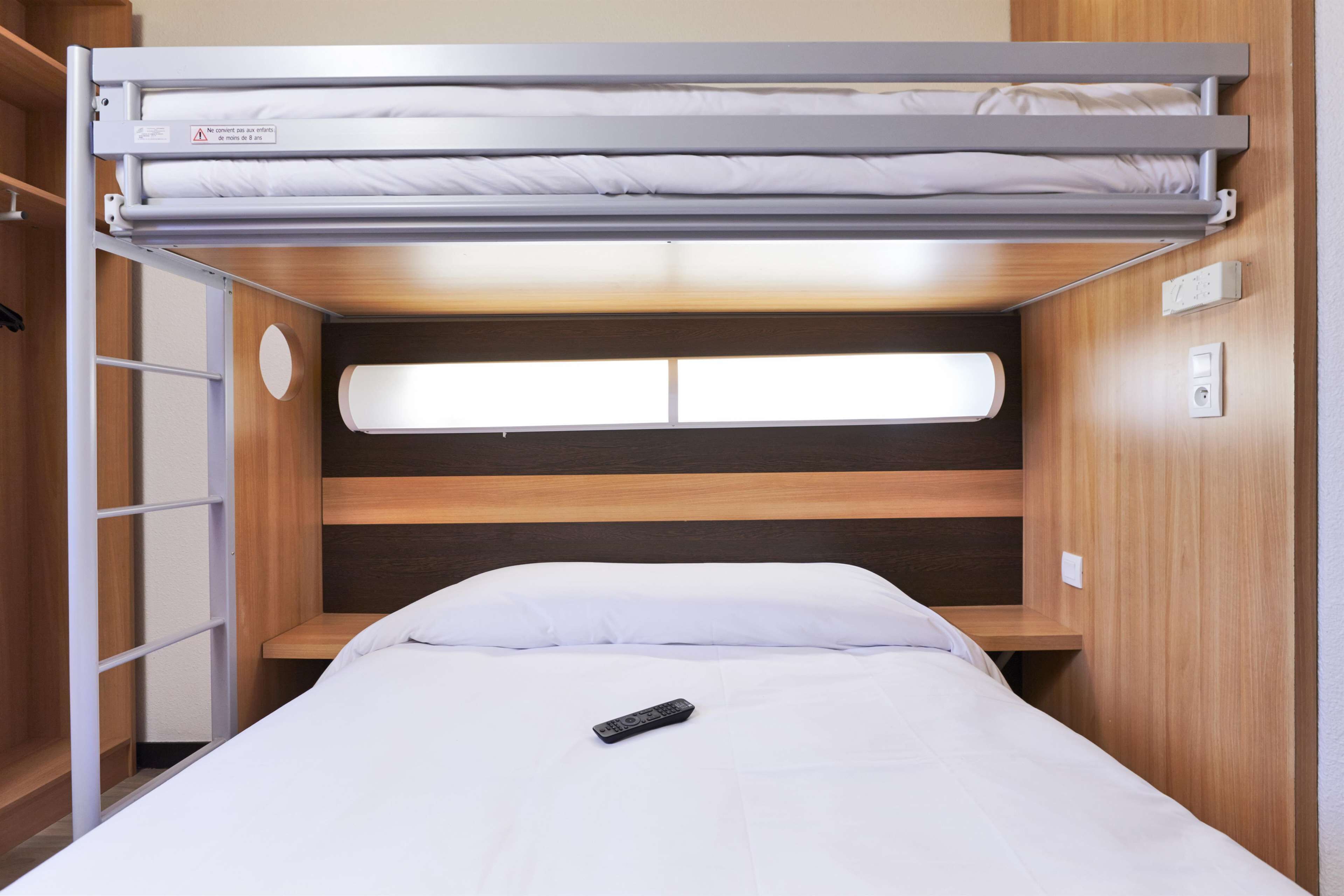 Un lit superposé avec un bureau escamotable et une fenêtre au-dessus du lit du bas.