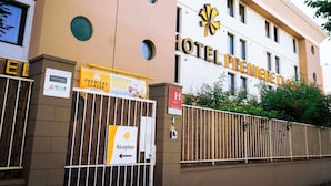Entrada de un hotel con un letrero que dice "HOTEL PREMIERE CLASSE" y un cartel de recepción señalando hacia la izquierda.