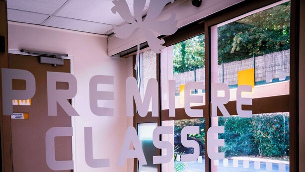 Entrada de un hotel con un letrero grande que dice "PREMIERE CLASSE HOTELS".