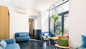 A modern lounge area with blue sofas, a wooden coffee table, and a hanging plant. - Hotel Piazza Bellini & Apartments (Naples)