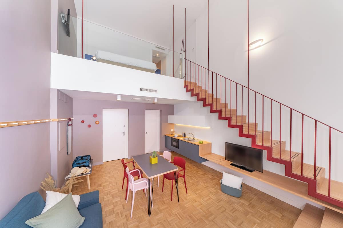 A modern apartment with a dining area, kitchen, and a staircase.