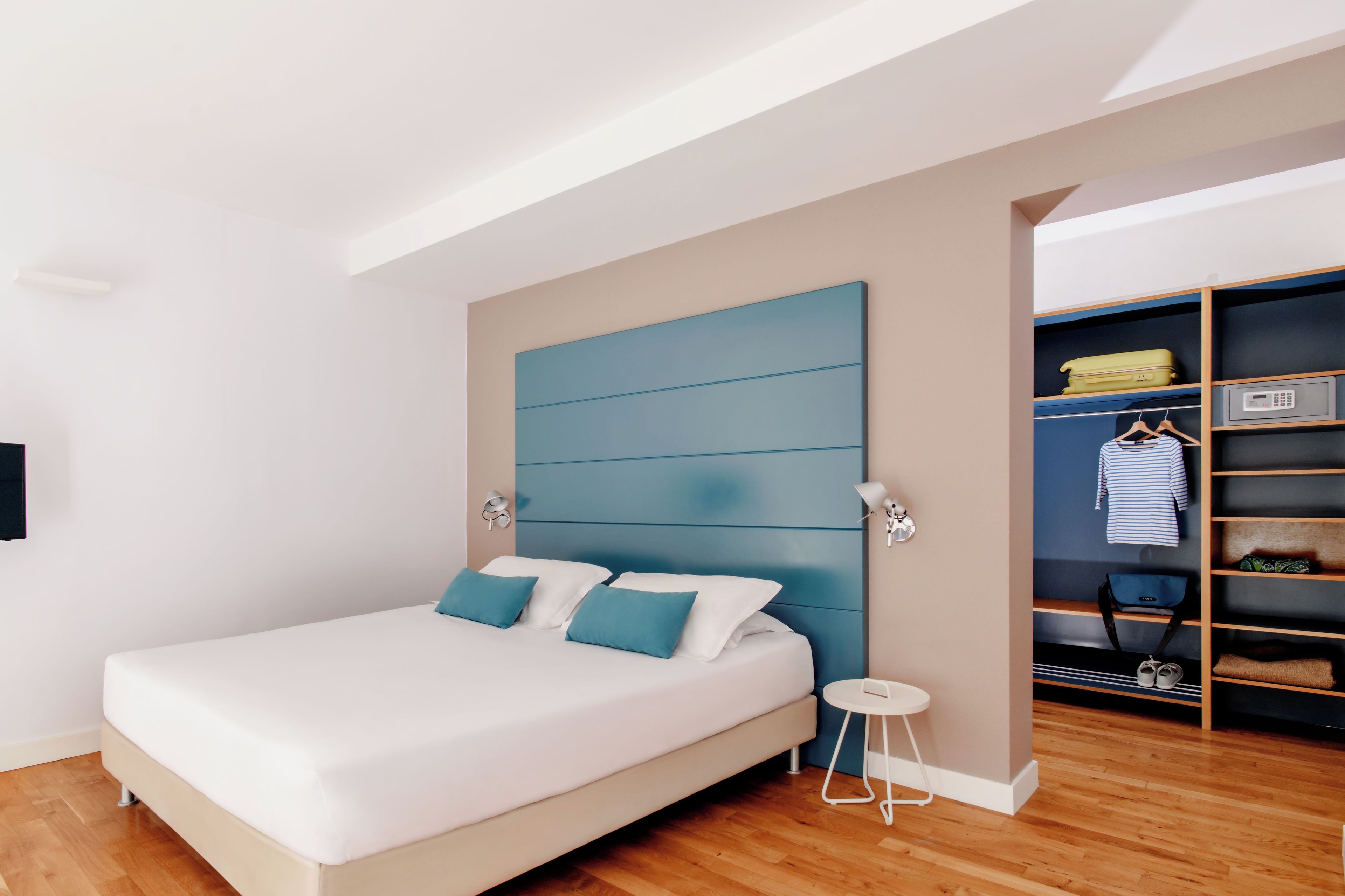 A modern bedroom with a large bed, a built-in wardrobe, and a small bedside table.