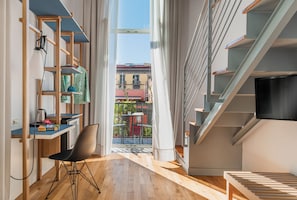 A modern apartment with a wooden desk, a chair, a TV, and a staircase. - Piazza Bellini (Naples)