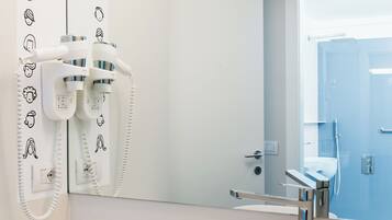 A modern bathroom with a white sink, a hairdryer, and a mirror.