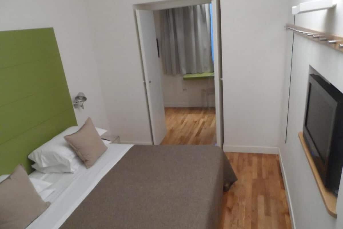 A bedroom with a bed, a television, and a green headboard.